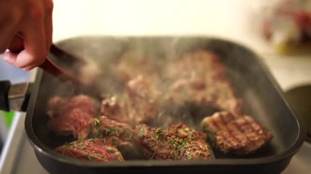 Schöne Steak Steak in der Pfanne gebraten. Kochen Sie mit einer Zange. dreht die Scherben um. Der Prozess des Kochens in der Küche. — Stockvideo