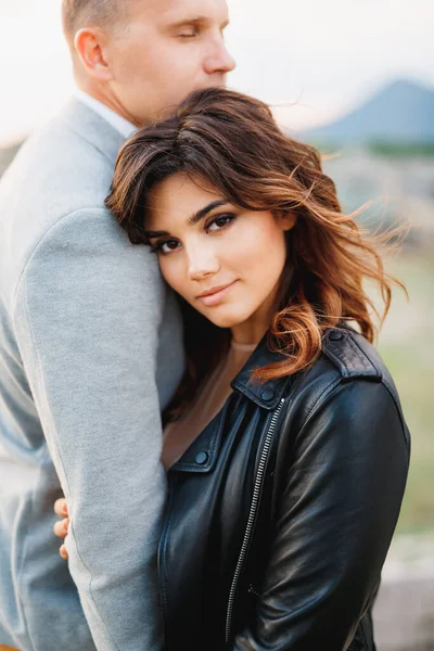 Beautiful serious girl in a black leather jacket put her head on the shoulder of man in a gray jacket — Stock Photo, Image