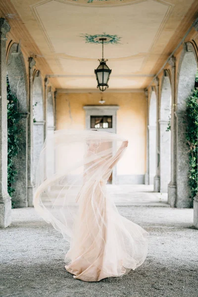 Pengantin dalam gaun pengantin berdiri menutupi dirinya dengan kerudung di teras berbantal tua. Danau Como — Stok Foto