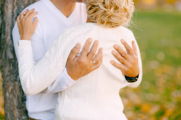 Mannen kramar kvinnan vid axlarna nära ett träd i höstskogen. Närbild — Stockfoto