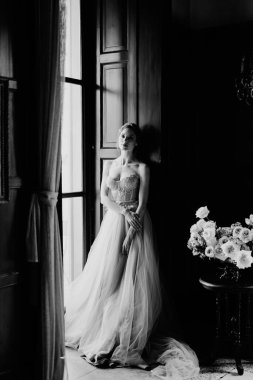 Gelin, eski bir villanın büyük penceresinin çerçevesine yaslanıyor. Como Gölü. Siyah beyaz fotoğraf