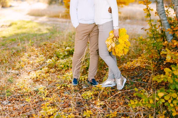 Mann umarmt Frau im Herbstwald. Frau mit einem Kranz aus gelben Blättern in der Hand — Stockfoto