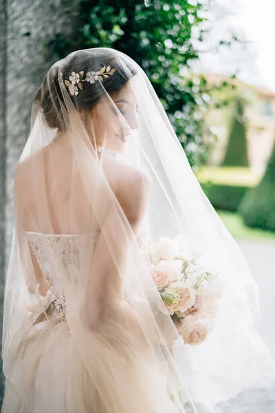 Pengantin dalam gaun pengantin dengan kerudung dan karangan bunga berdiri dengan kepalanya menghadap dinding. Danau Como. Pandangan ke belakang. Tutup. — Stok Foto