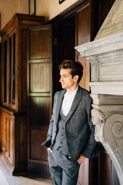 Damat şöminenin yanındaki bir odada eski bir villadaki dolapların arkasında duruyor. Como Gölü