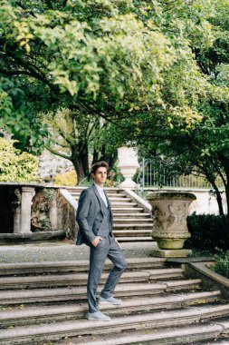 Parktaki merdivenlerde eli cebinde duran ciddi bir damat. Como Gölü