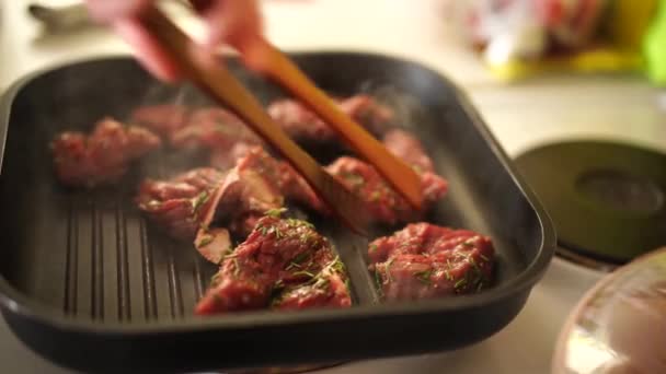 Zbliżenie kucharza restauracji w rękawiczkach stawia stek na patelni grillowej. Kucharz piecze soczysty kawałek mięsa na patelni grilla w restauracji. — Wideo stockowe