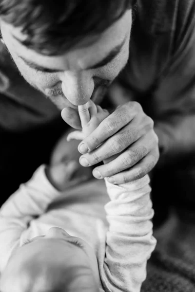 O pai beija as mãos minúsculas dos bebés. Close-up. Foto em preto e branco — Fotografia de Stock