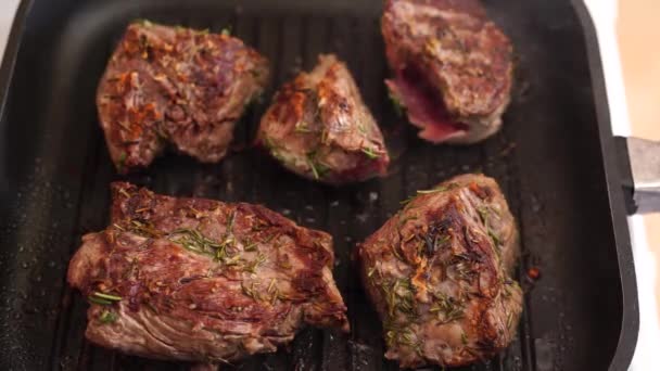 Morceaux frits de steak de boeuf dans une poêle, saupoudrés de romarin. — Video