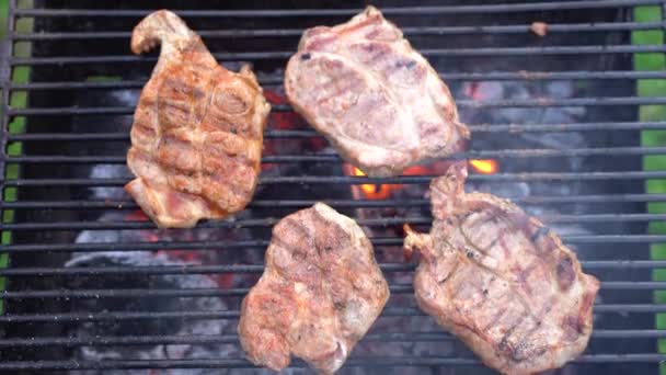 Quattro bistecche sono fritte su una griglia nera di metallo. — Video Stock