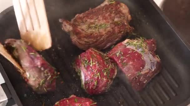 Pezzi di bistecca vengono fritti dallo chef in padella, in olio d'oliva e rosmarino. — Video Stock