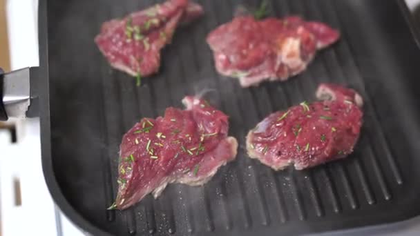 Cuatro filetes crudos se fríen en una sartén a la parrilla. — Vídeos de Stock