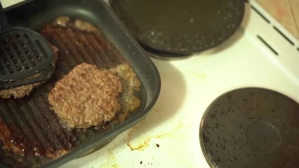 Burger pasteitjes worden gebakken in een grill pan op het fornuis. — Stockvideo