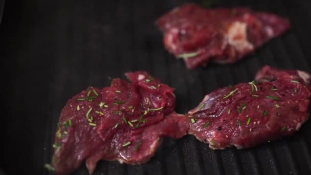 Όμορφα κόκκινο ωμό κρέας μπριζόλες τοποθετούνται στο τηγάνι σχάρα. — Αρχείο Βίντεο