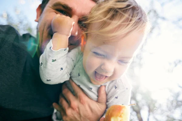 Ayah tersenyum memegang anak tertawa di depannya dengan pir di tangannya. Close-up. Sudut rendah — Stok Foto