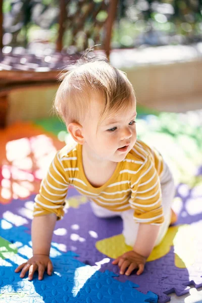 Liten baby kryper på en färgad matta på balkongen — Stockfoto