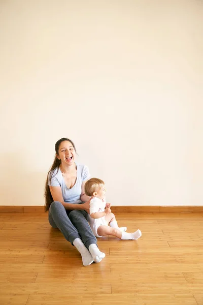 Tersenyum ibu dan gadis kecil duduk di lantai — Stok Foto
