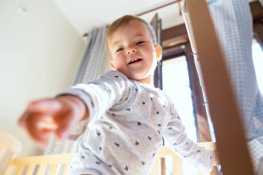 Gülümseyen bebek beşiğinde duruyor. Düşük açı