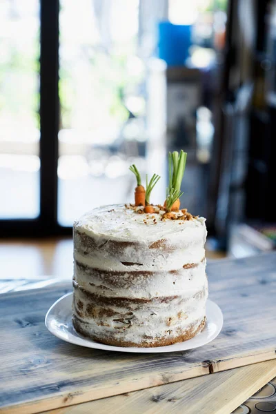 Bolo de cenoura fica em um prato branco na mesa na cozinha — Fotografia de Stock