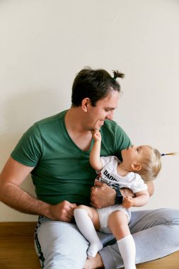 At kuyruklu baba kucağında küçük bir kız tutuyor.