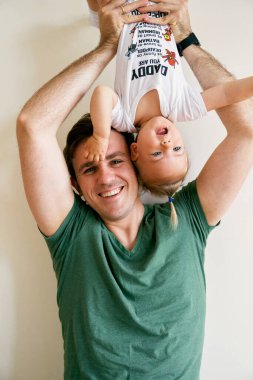 Gülümseyen baba küçük çocuğu baş aşağı büyüttü.