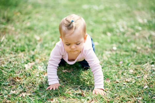 Pequeña linda chica arrastrándose en un prado verde —  Fotos de Stock