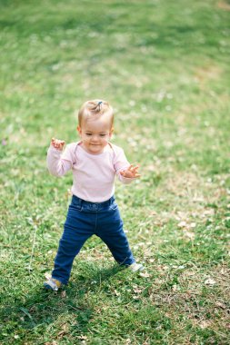 Küçük komik kız yeşil bir çayırda duruyor