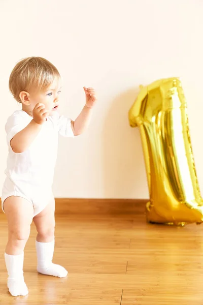 Liten flicka står på golvet i rummet mot bakgrund av en uppblåsbar figur en — Stockfoto