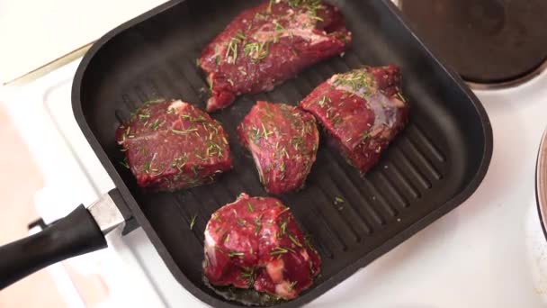 Bellissimi pezzi rossi di carne scoppiettanti su una padella nera. Le grandi bistecche cotte a vapore crude sono arrostite ad alto calore. — Video Stock