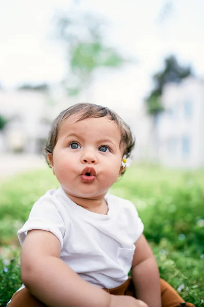 Bambina seduta sul prato con la bocca aperta — Foto Stock