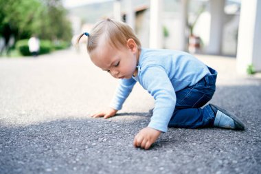 At kuyruklu küçük kız parkta dizlerinin üzerinde oturuyor.