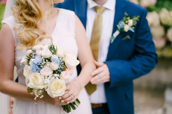 Наречений ніжно торкається руки наречених, тримаючи букет під час весільної церемонії — стокове фото