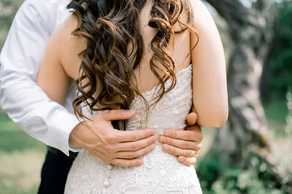 Der Bräutigam umarmt die Braut sanft. Hände des Bräutigams auf der Taille der Braut, Nahaufnahme — Stockfoto