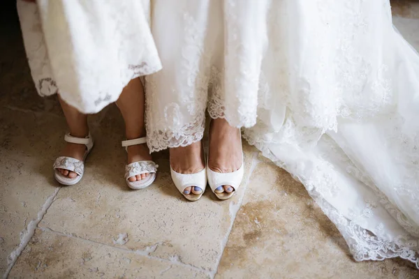 Legs of the bride in white shoes and a little girl in sandals next to her, top view — Stok Foto