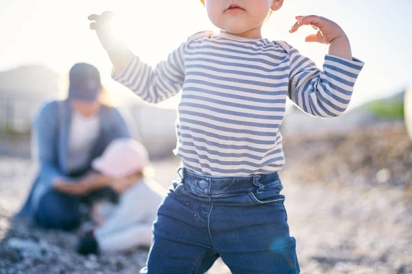 Kid stands with his hands up against the background of a man with a child. Close-up