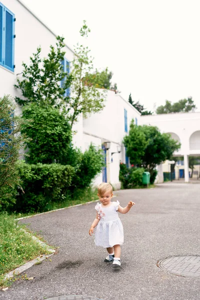 Little girl walks on the asphalt in the yard of the house Royalty Free Stock Images