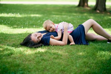 Annem küçük bir kızla birlikte yeşil bir çimenlikte yatıyor.