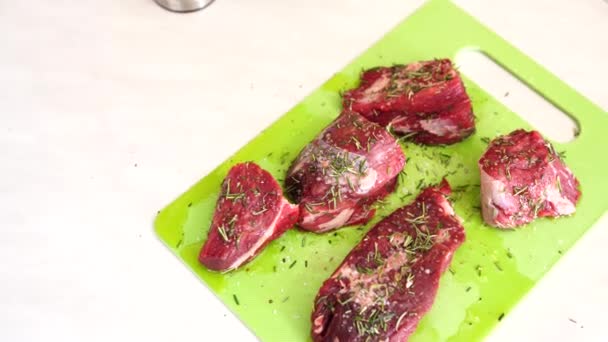 Nyers steak darabok egy zöld vágódeszkán, sóval és rozmaringgal megszórva, napraforgóolajjal töltve. — Stock videók