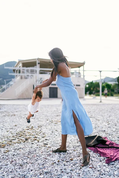 Ibu berdiri di pantai dan ayunan gadis kecil dengan lengan — Stok Foto