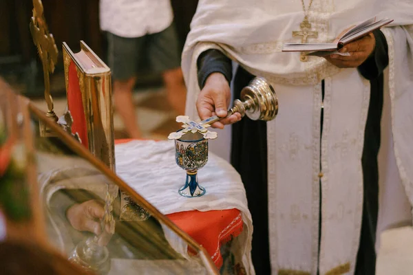 Priester zit de dienst voor, houdt de Bijbel en het kruis in zijn hand — Stockfoto