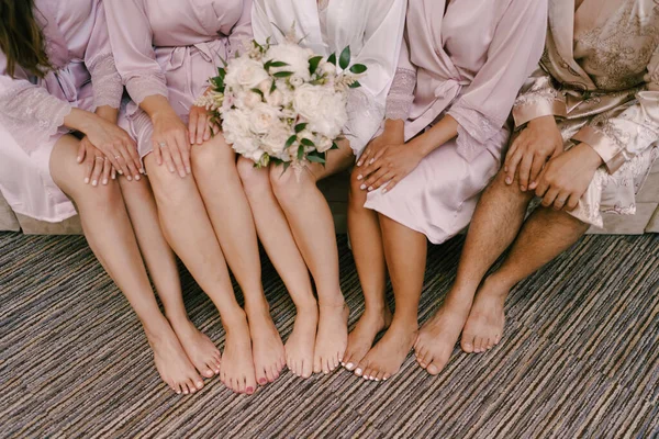 Grote voeten van bruidsmeisjes en bruid met een boeket bloemen — Stockfoto