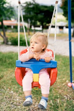 Çocuk salıncakta sallanıyor ve kafasını çeviriyor.