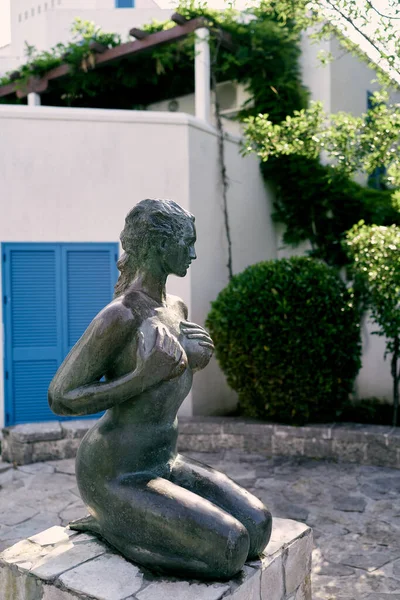 Monument to a kneeling girl on a pedestal stands on a cobbled area near the building — Stock Photo, Image