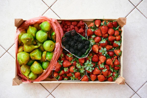 Kit de madera con cajas de fresas, frambuesas, higos y moras se encuentra en una baldosa ligera —  Fotos de Stock