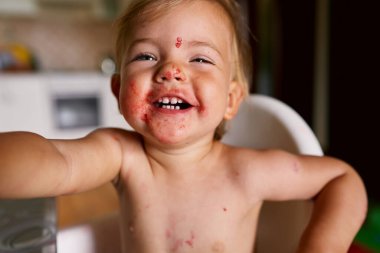 Kirli yüzlü, gülen bir çocuk.