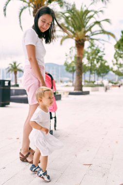 Annem kaldırım kenarında dururken küçük bir kızın elini tutuyor.