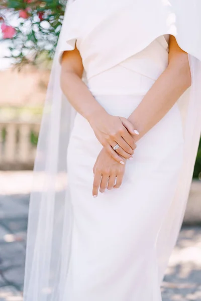 Handen van de bruid met manicure in een witte jurk met een sluier. Close-up — Stockfoto