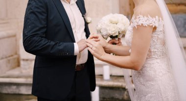 Bir buket gülle gelin damat parmağına yüzük takar