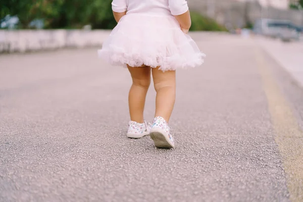 アスファルトの道路上に立つふわふわのスカートの少女の足 — ストック写真