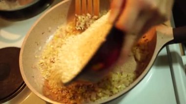 Pirinci kaseden tavadaki haşlanmış soğanlara döküyorum.