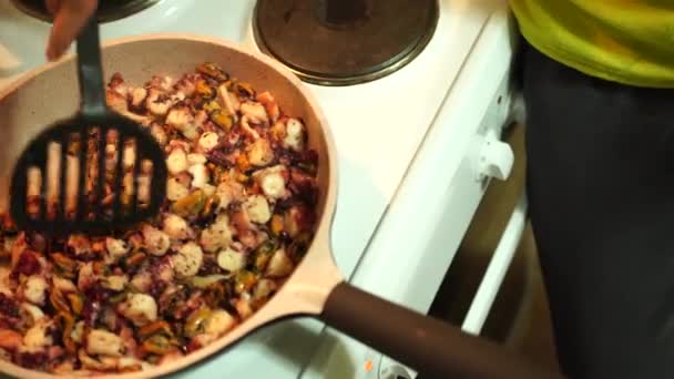 Muž míchá mořské jídlo v pánvi na sporáku špachtlí. Vaření italského jídla. — Stock video